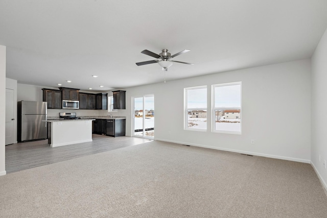 unfurnished living room with recessed lighting, light colored carpet, baseboards, and ceiling fan