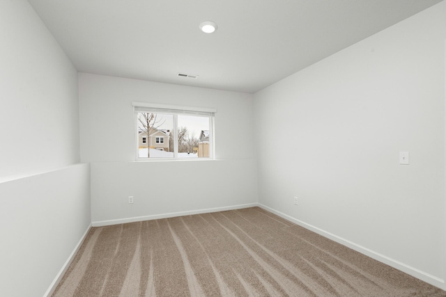 carpeted spare room featuring visible vents and baseboards