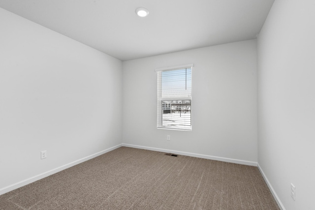 carpeted spare room featuring visible vents and baseboards