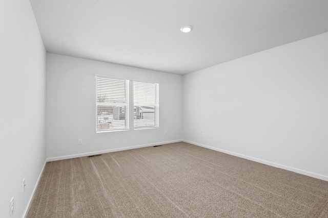 spare room with visible vents, baseboards, and light colored carpet