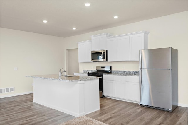 kitchen featuring light wood finished floors, visible vents, appliances with stainless steel finishes, white cabinetry, and a kitchen island with sink