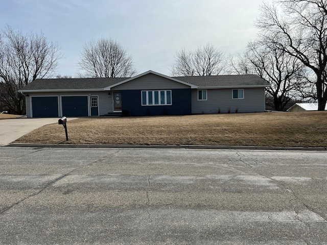 view of front of house featuring a front lawn, concrete driveway, and a garage