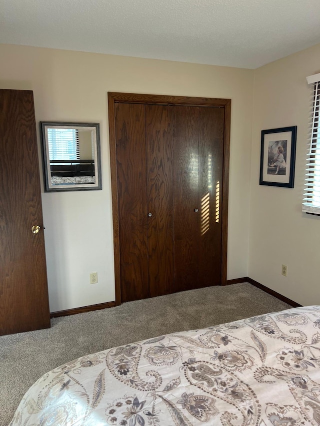 carpeted bedroom featuring baseboards, a closet, and a textured ceiling