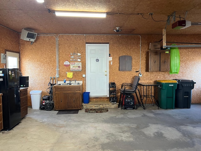 garage with a garage door opener, freestanding refrigerator, and a sink