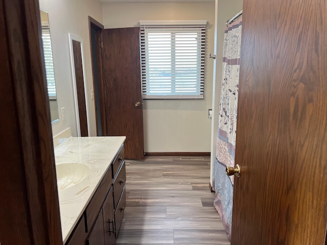 full bathroom featuring vanity, wood finished floors, and baseboards