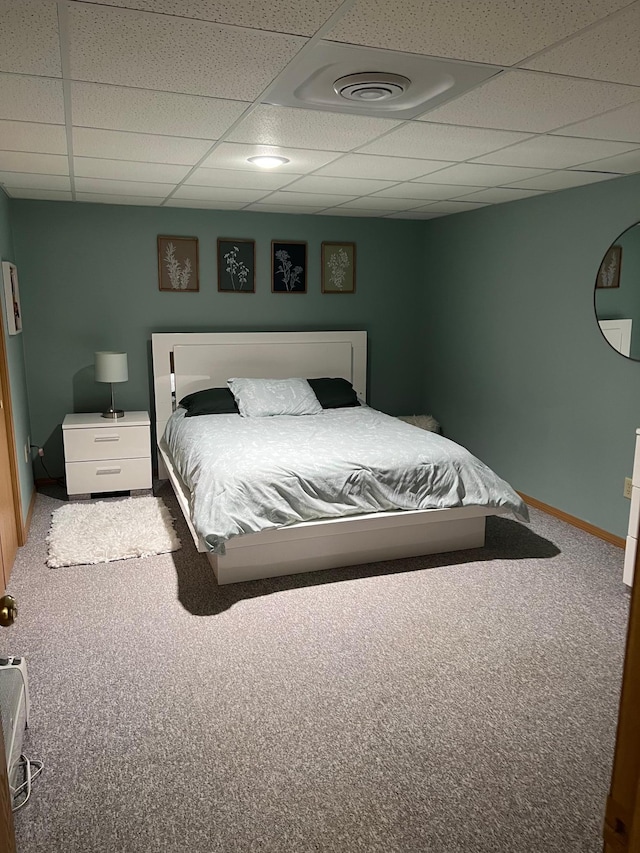 carpeted bedroom with baseboards and a paneled ceiling