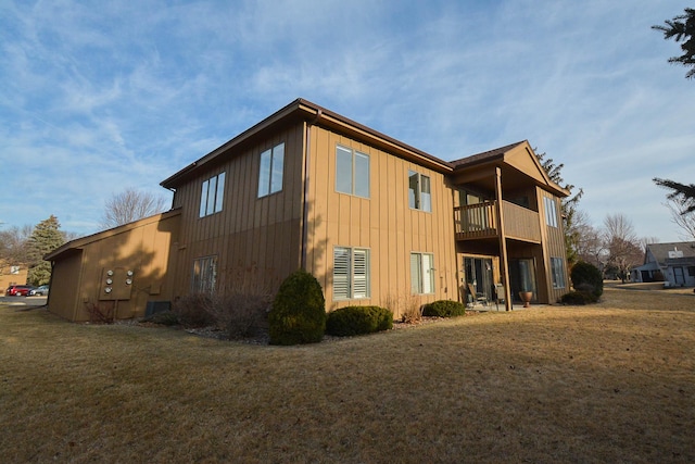 back of property with a balcony, a yard, and board and batten siding