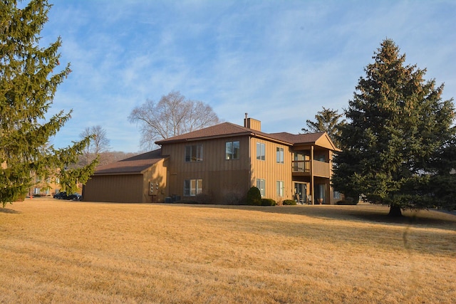 back of property featuring a balcony, a yard, central AC, and a chimney