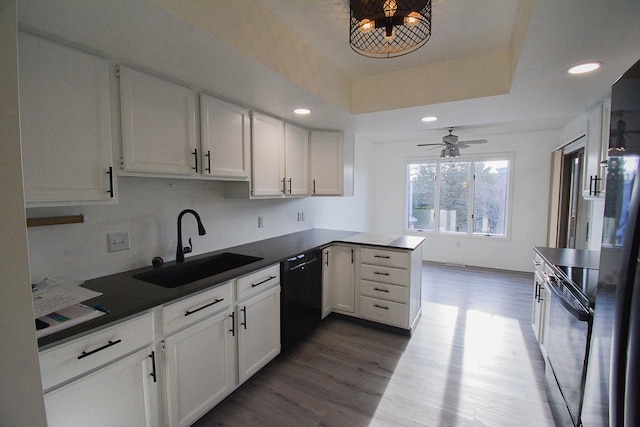 kitchen with a sink, a tray ceiling, black appliances, and white cabinets