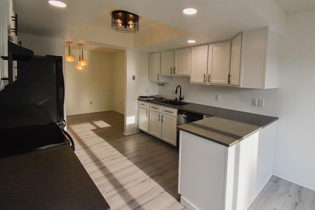 kitchen featuring dark countertops, black fridge, light wood finished floors, and a sink