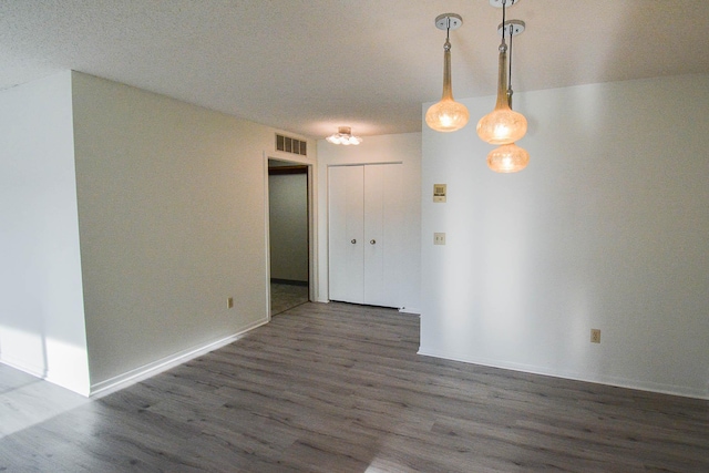 spare room featuring wood finished floors, visible vents, and baseboards