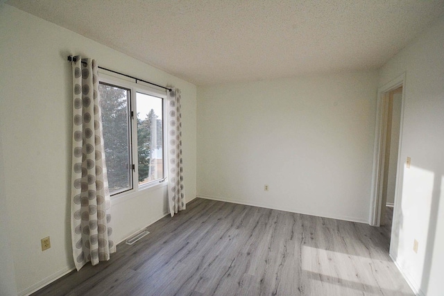 empty room featuring wood finished floors and visible vents