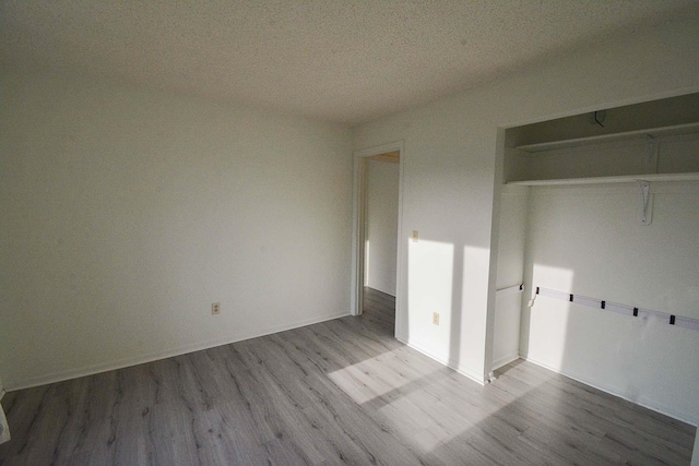 unfurnished bedroom with wood finished floors, a closet, and a textured ceiling