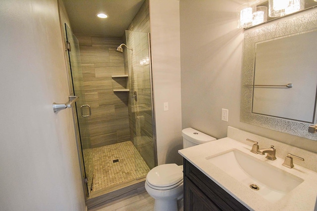 bathroom with vanity, toilet, wood finished floors, and a shower stall