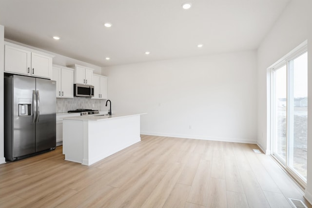 kitchen with tasteful backsplash, light wood-style flooring, stainless steel appliances, and a sink