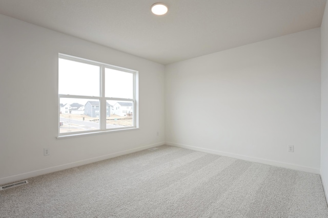 carpeted spare room featuring visible vents and baseboards