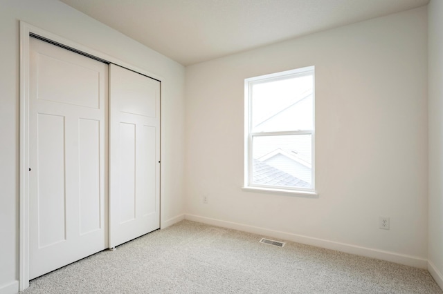 unfurnished bedroom with carpet, visible vents, a closet, and baseboards