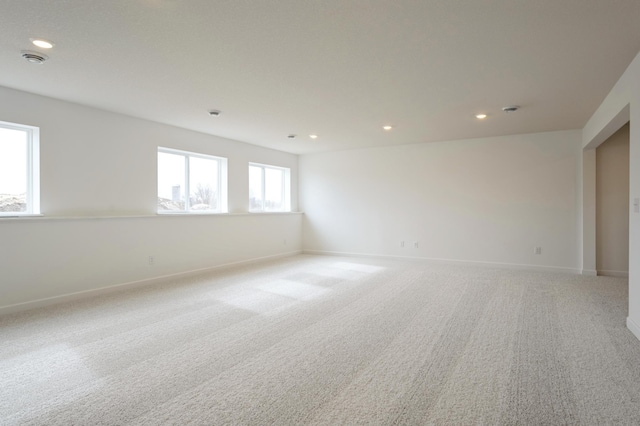 spare room featuring light carpet, recessed lighting, and baseboards