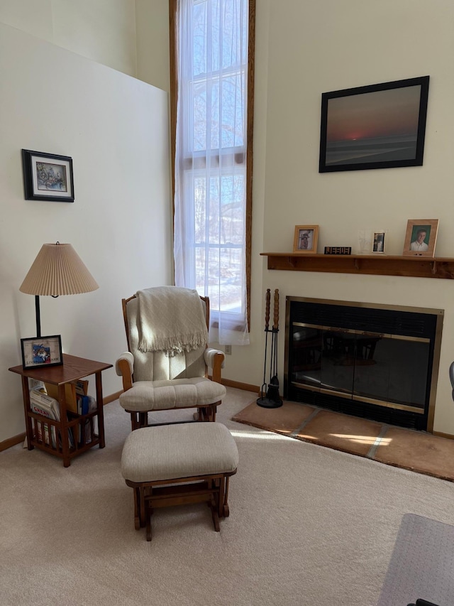 living area featuring a glass covered fireplace, baseboards, and carpet floors