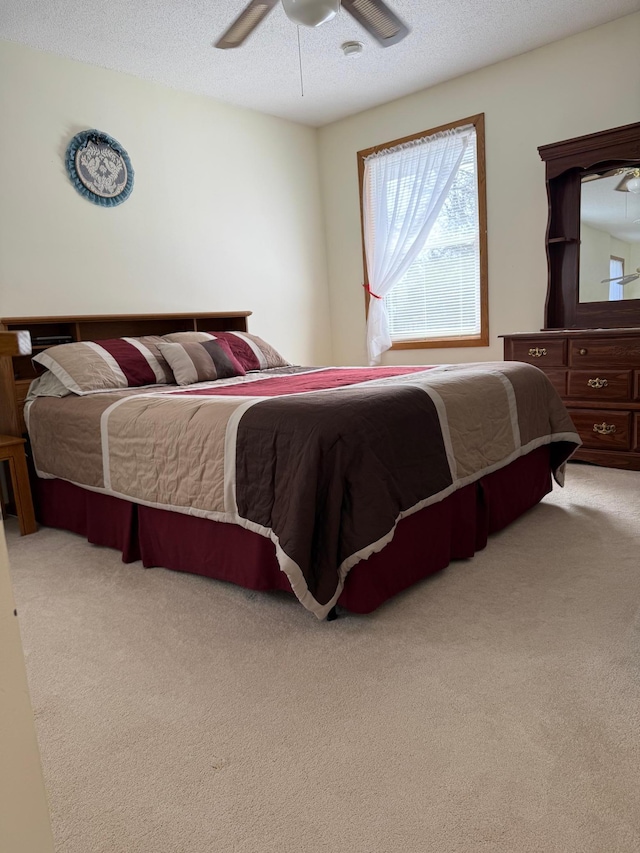 bedroom with a ceiling fan, carpet, and a textured ceiling