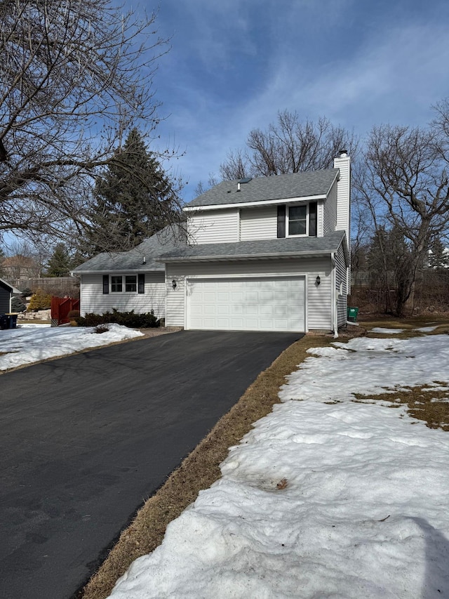 traditional-style home with aphalt driveway, a garage, and a chimney