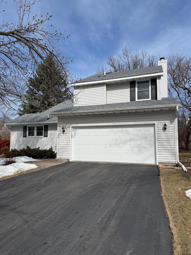 view of front of home featuring aphalt driveway, a garage, and a chimney