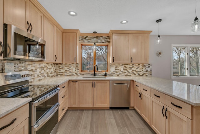 kitchen featuring light brown cabinets, stainless steel appliances, and a sink