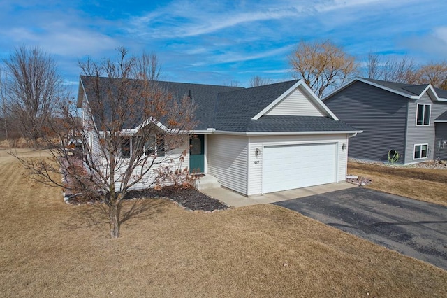 ranch-style home featuring a front yard, an attached garage, driveway, and roof with shingles