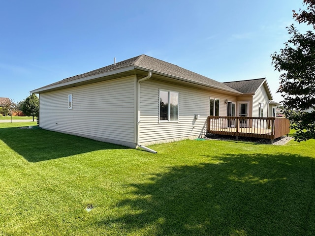 view of property exterior with a yard, a wooden deck, and a shingled roof