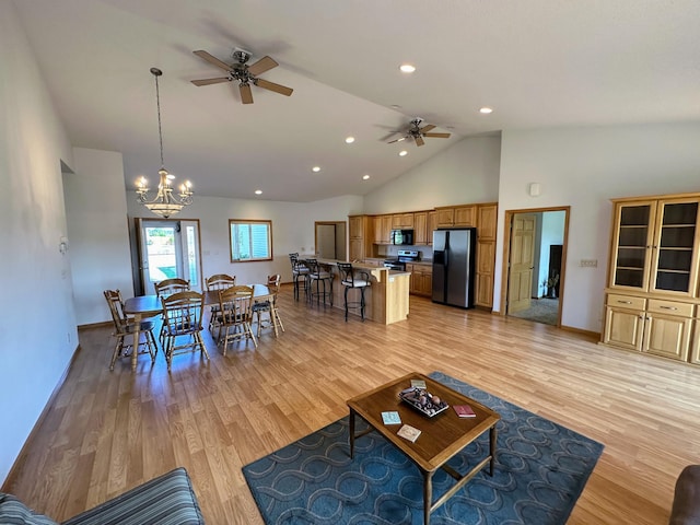 living area featuring light wood-type flooring, baseboards, high vaulted ceiling, and ceiling fan with notable chandelier