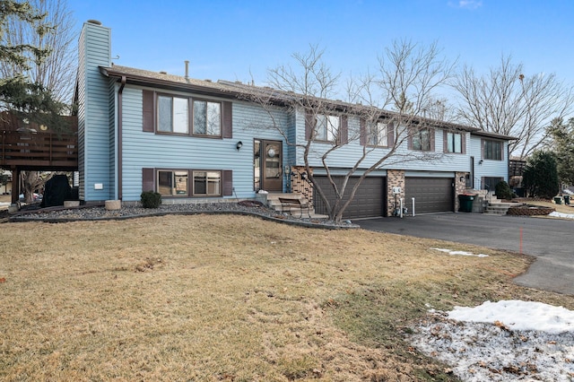 raised ranch with a garage, a front yard, a chimney, and aphalt driveway