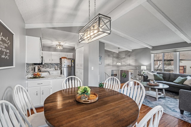 dining room with dark wood finished floors, beamed ceiling, and a textured ceiling