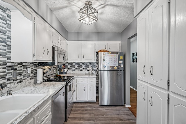 kitchen with dark wood finished floors, stainless steel appliances, a textured ceiling, white cabinetry, and a sink