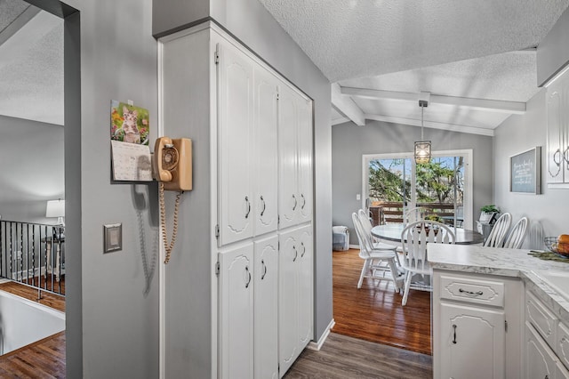 kitchen featuring white cabinetry, lofted ceiling with beams, light countertops, dark wood-style floors, and a textured ceiling