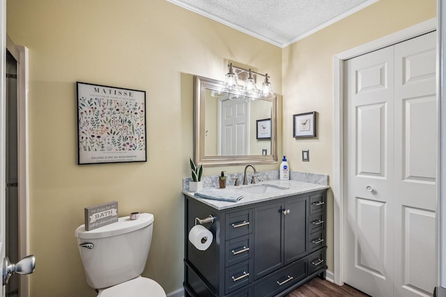 bathroom with toilet, a textured ceiling, wood finished floors, crown molding, and vanity