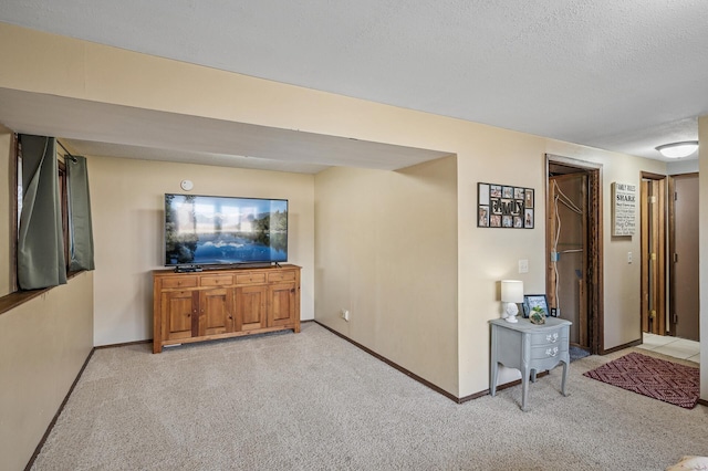 interior space featuring light colored carpet, baseboards, and a textured ceiling