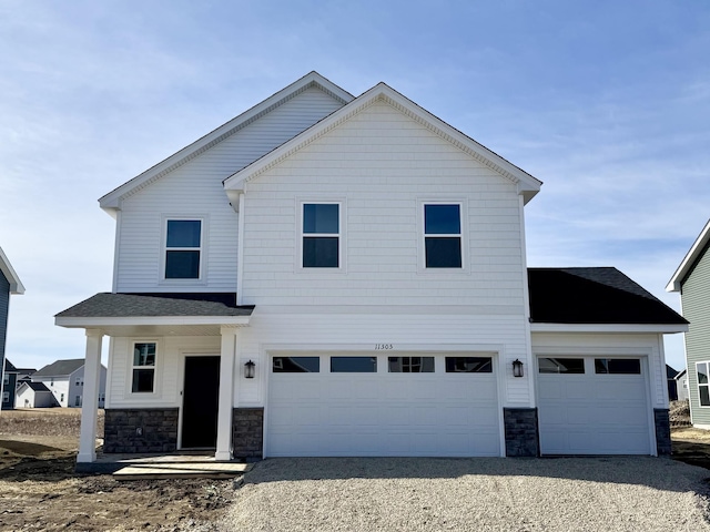 view of front of house with stone siding, an attached garage, and driveway