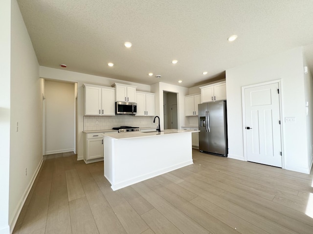 kitchen featuring decorative backsplash, appliances with stainless steel finishes, white cabinetry, and light wood-style floors