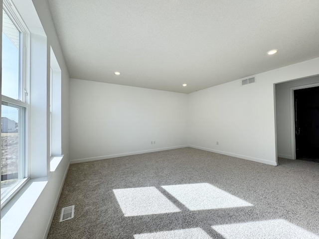 carpeted empty room with visible vents, baseboards, and a healthy amount of sunlight