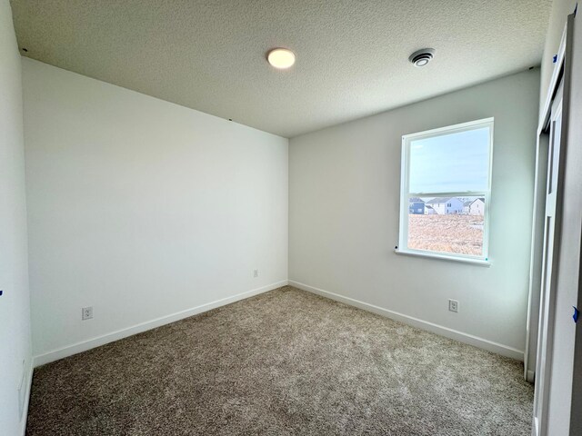 unfurnished bedroom with a textured ceiling, baseboards, and carpet floors