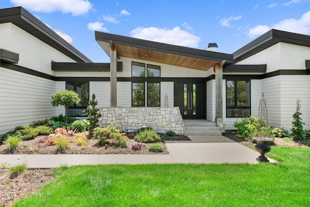 exterior space with a yard, french doors, and stone siding