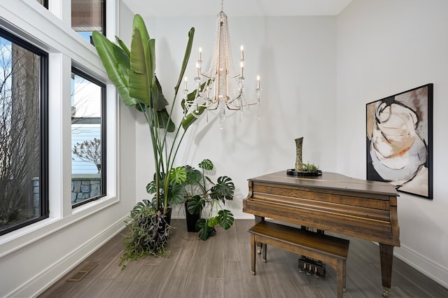 interior space featuring visible vents, wood finished floors, baseboards, and a chandelier