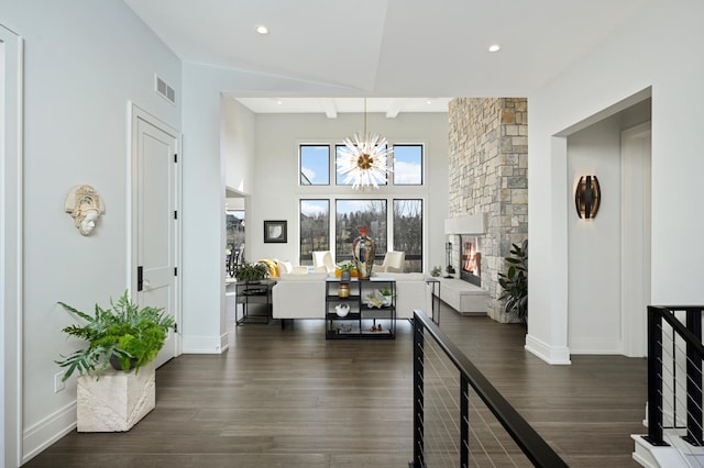 foyer entrance with visible vents, an inviting chandelier, dark wood-style floors, and a fireplace