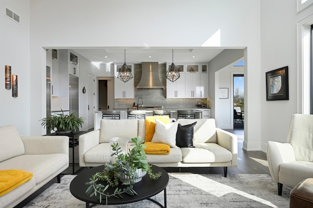 living area featuring dark wood-style floors, visible vents, a high ceiling, and baseboards