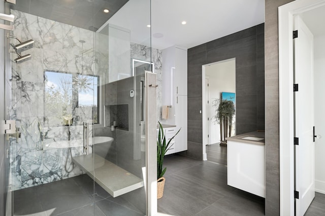 full bathroom with recessed lighting, vanity, tile walls, and a shower stall