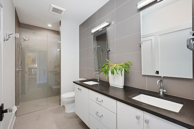 bathroom featuring a sink, visible vents, tile walls, and a shower stall