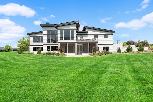 back of property featuring a balcony, a yard, and a sunroom