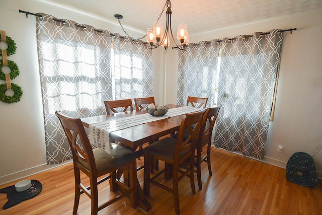 dining space featuring a notable chandelier, baseboards, and light wood-style floors