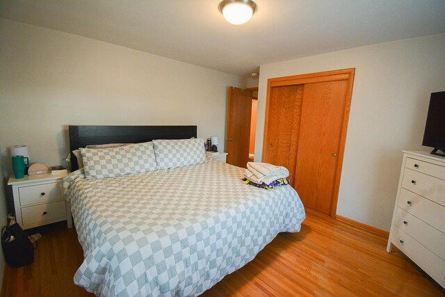 bedroom with wood finished floors, a closet, and baseboards