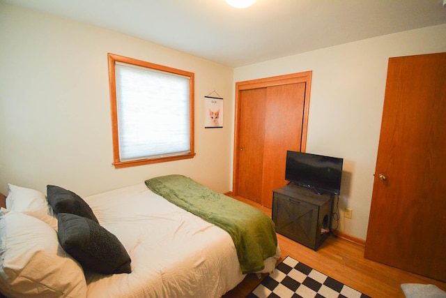 bedroom featuring a closet, light wood-style flooring, and baseboards